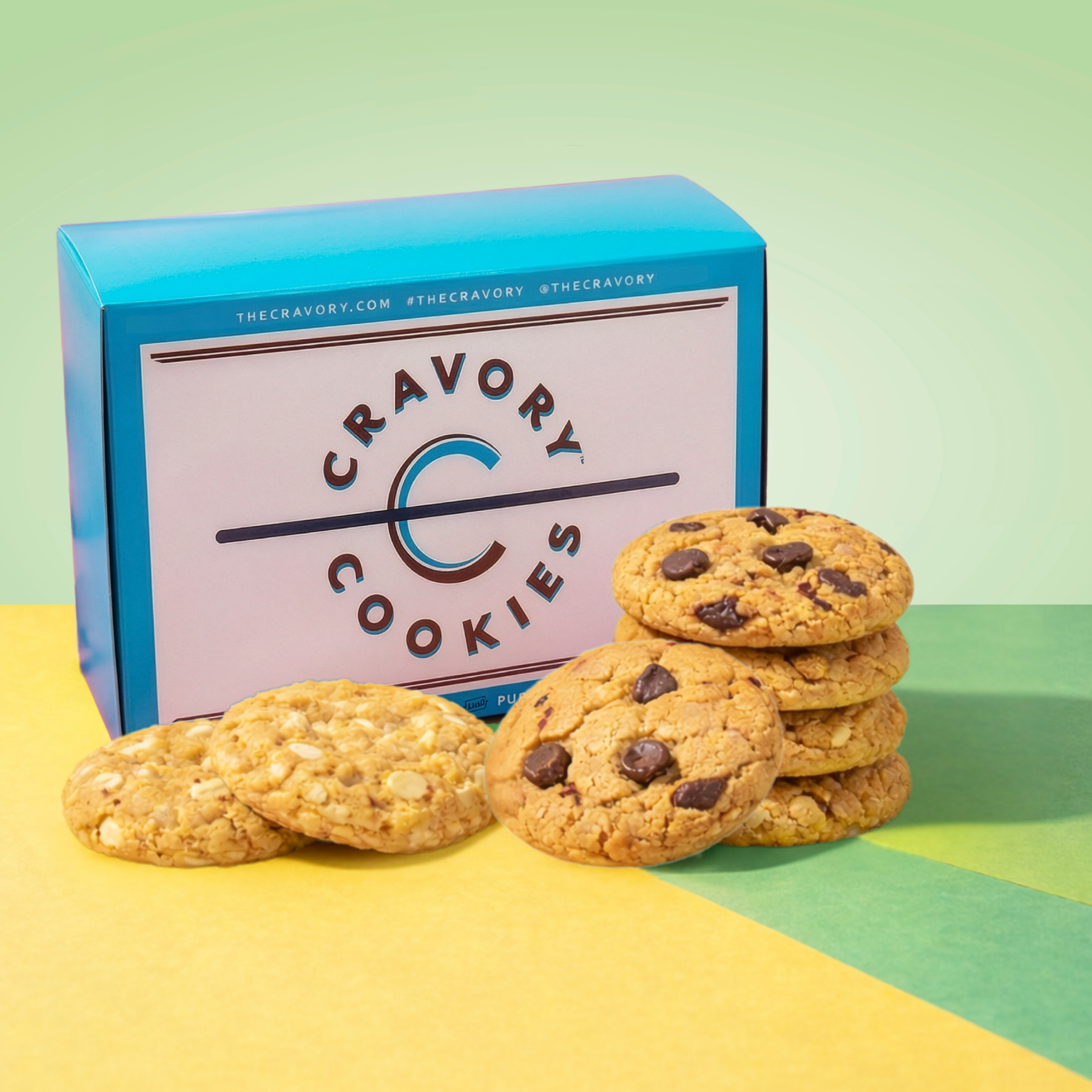 Cookies with chocolate chips in front of a Cravory Cookies box on a colorful background