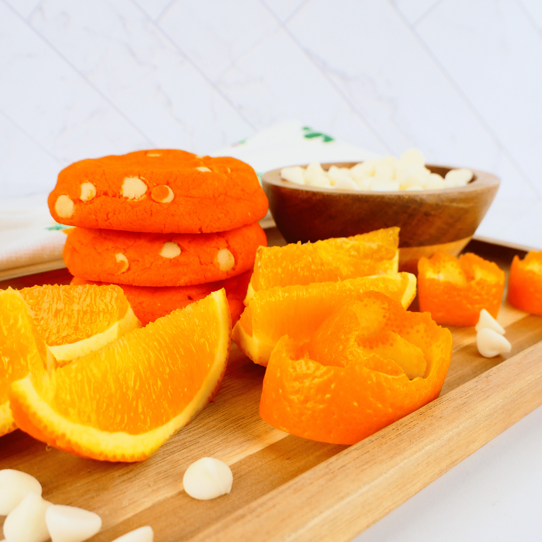 Orange slices and peeled oranges on a wooden board with a white background with orange popsicle cookies