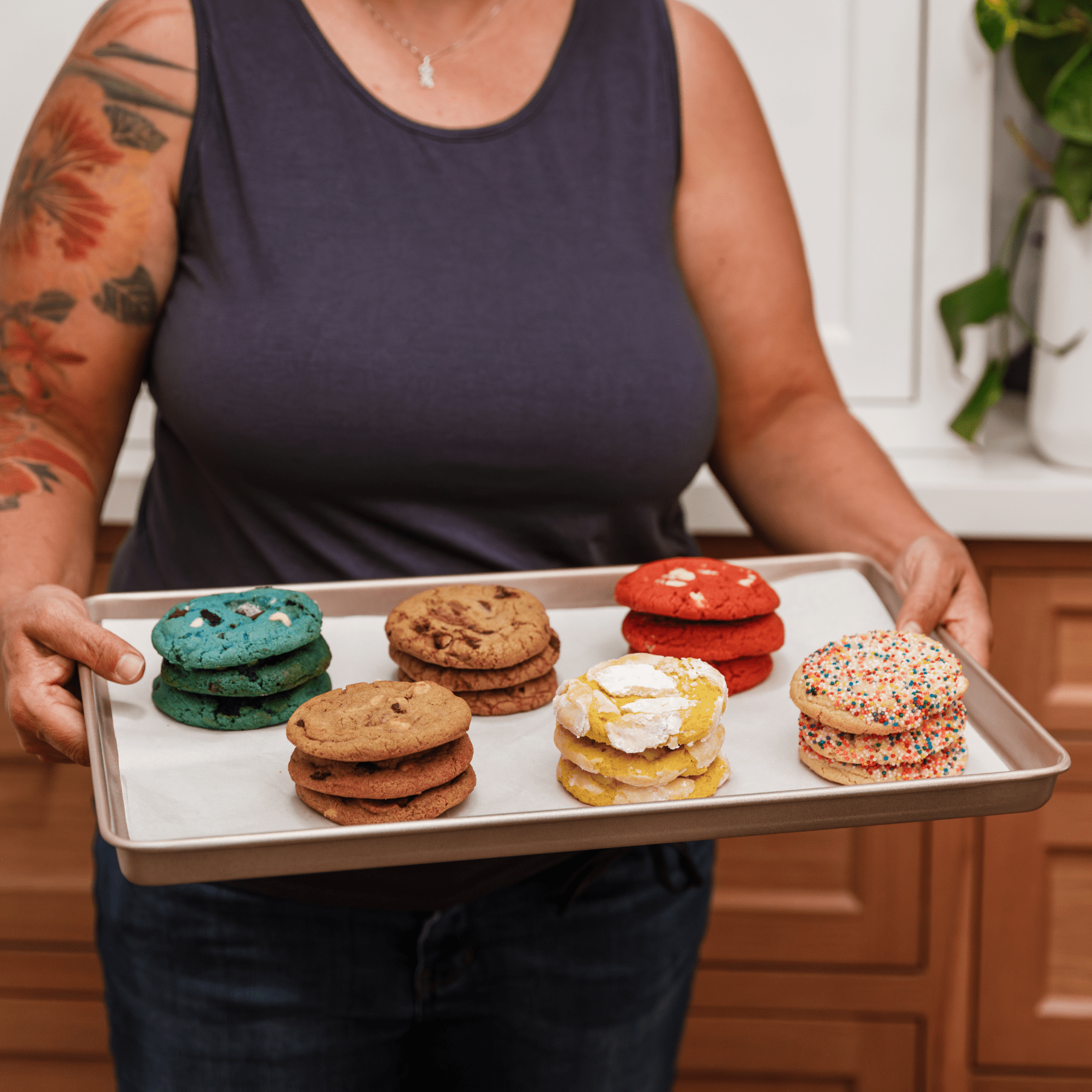 Person holding a baking sheet with assorted cookies