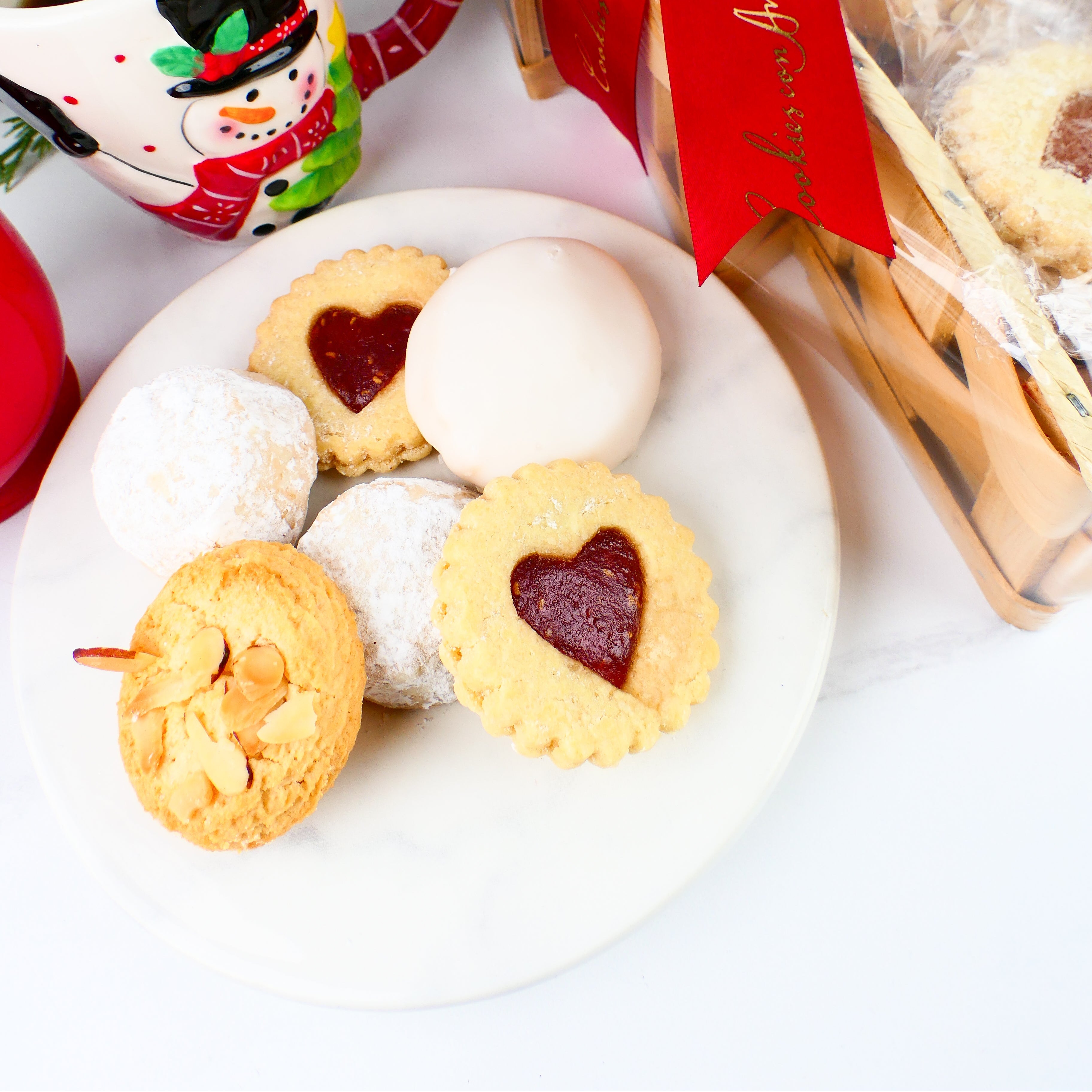 Assorted cookies on a plate with a mug and gift box in the background