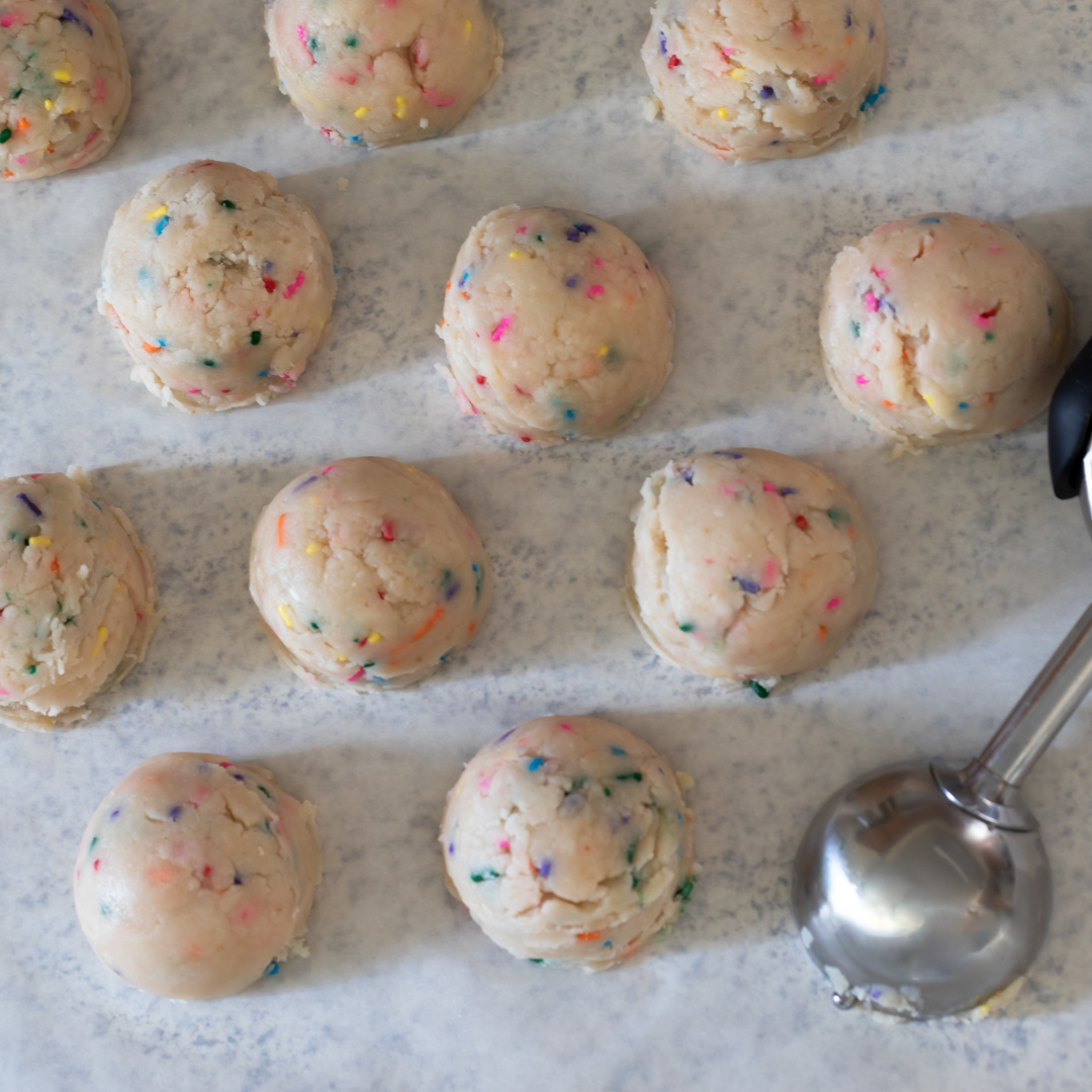 How To Make Birthday Cake Cookie Dough? Cookie dough mixed with sprinkles, rolled into balls and placed on parchment paper