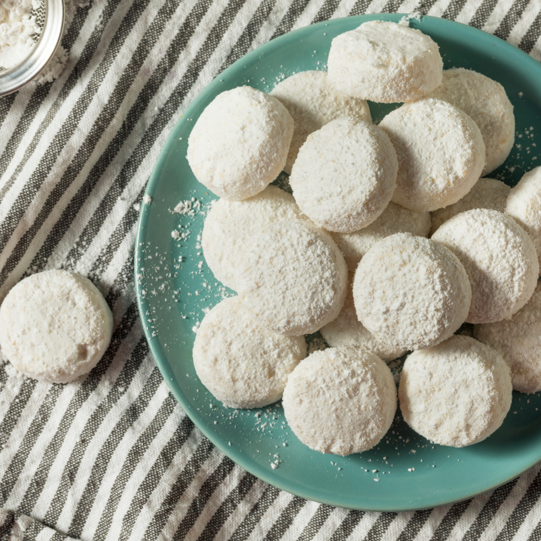 How To Make Italian Wedding Cookies - Small bite sized cookies covered in powdered sugar on a green plate