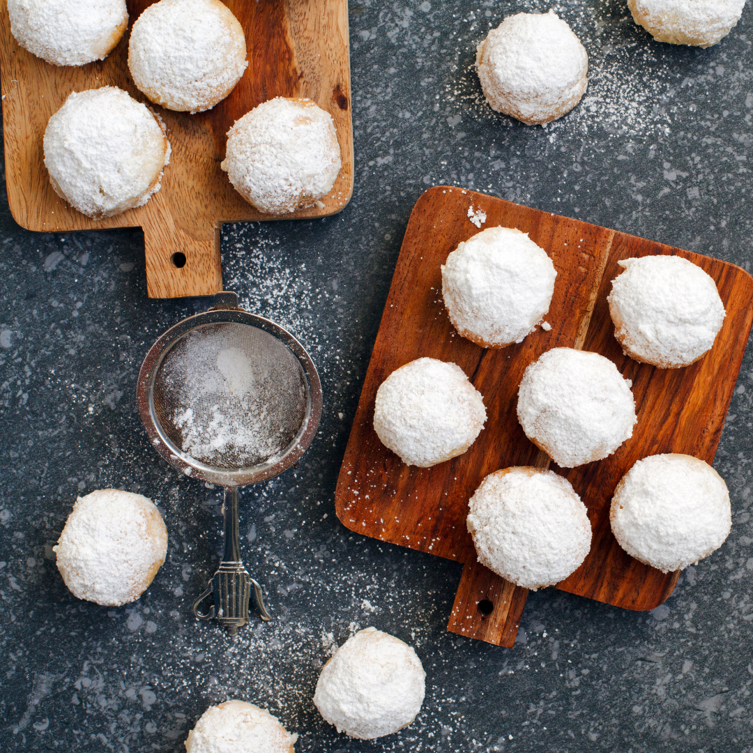 How to Make Mexican Wedding Cookies - small bite sized cookies sprinkled with powered sugar and presented on a wooden cutting board