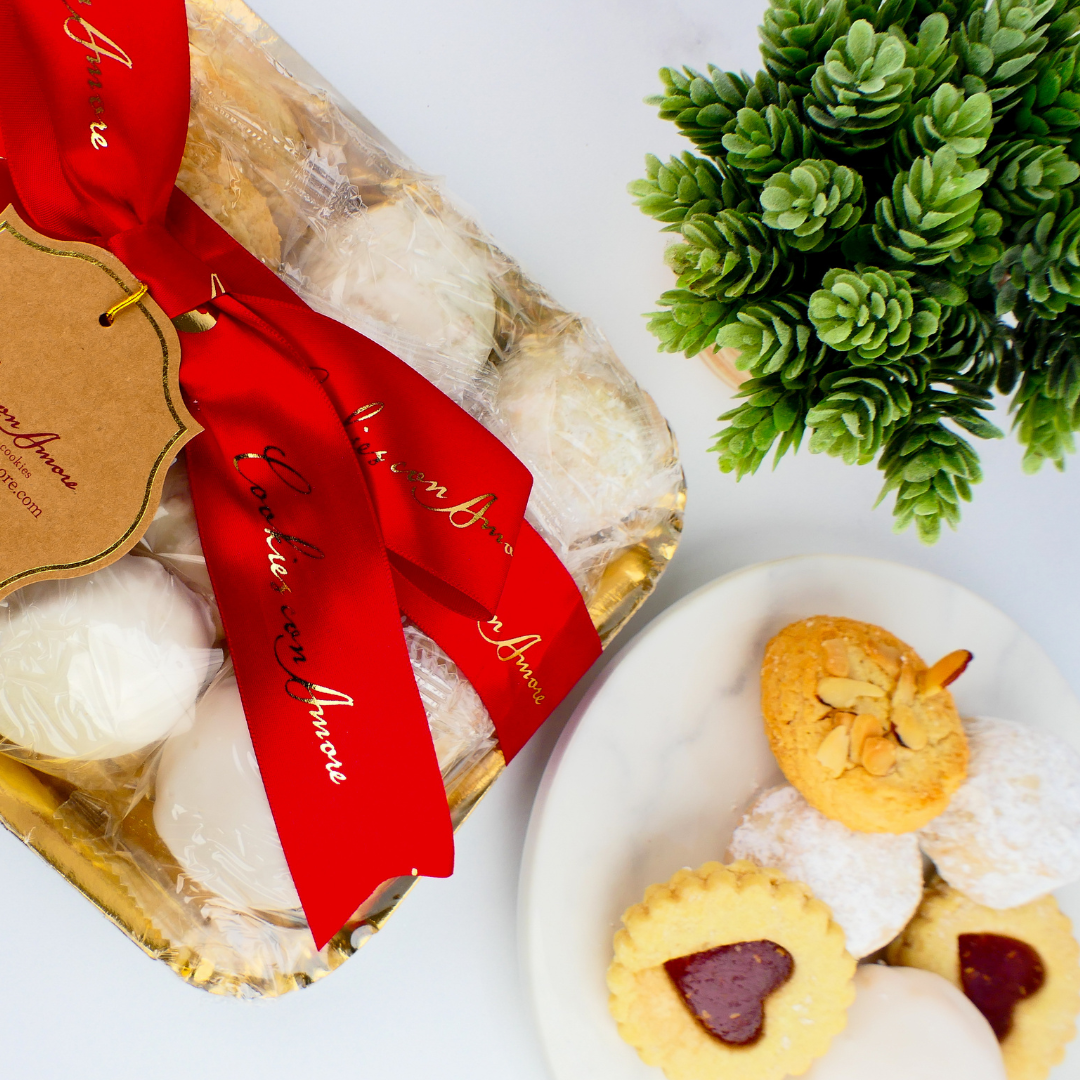 Packaged cookies with a red ribbon and a small potted plant on a white surface