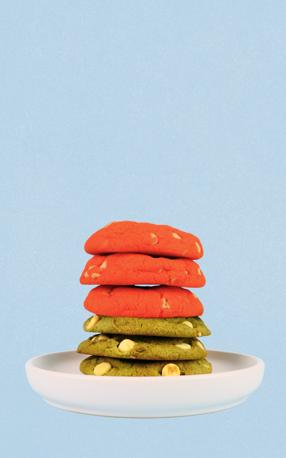 Stack of colorful cookies on a white plate against a light blue background
