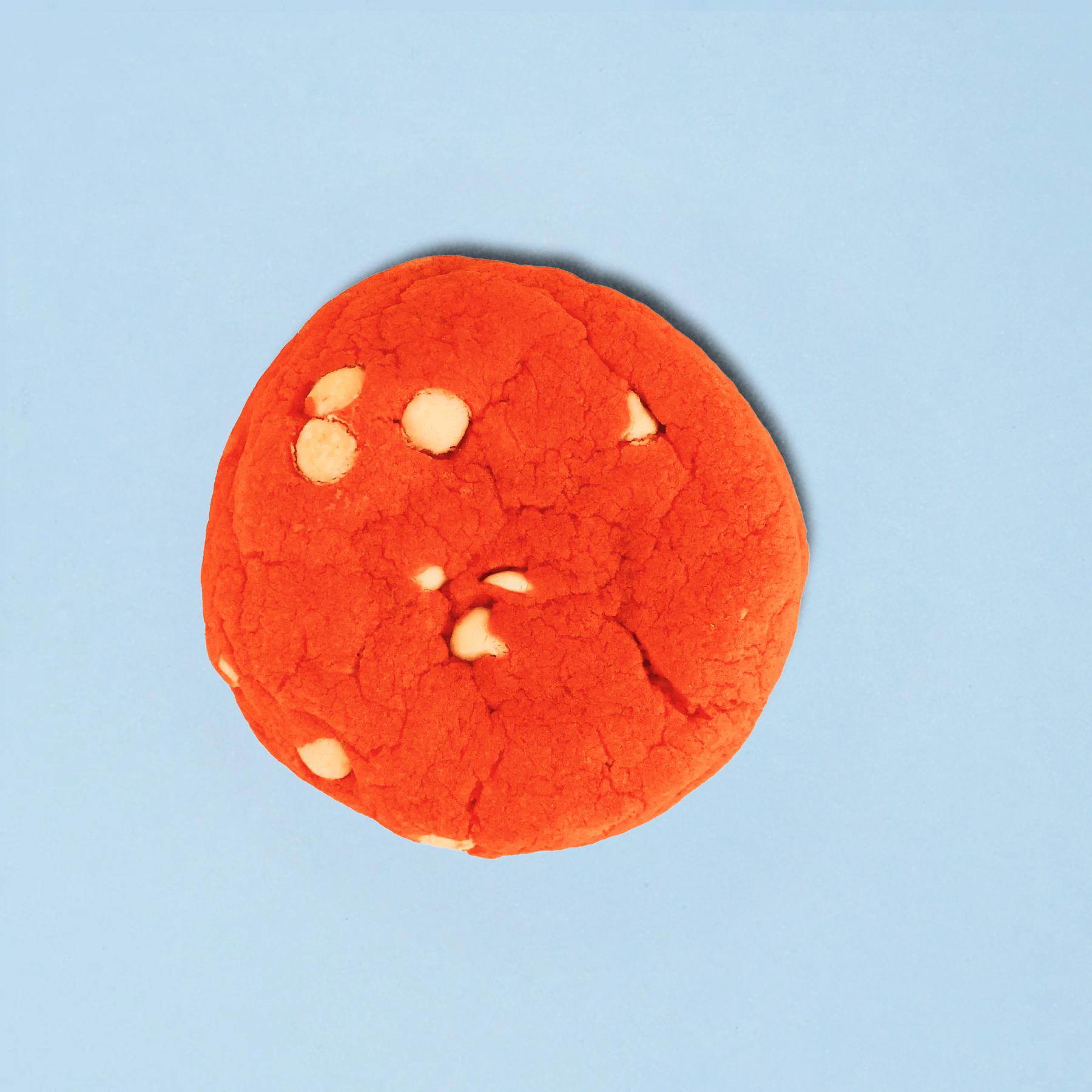 Red cookie with white chips on a light blue background