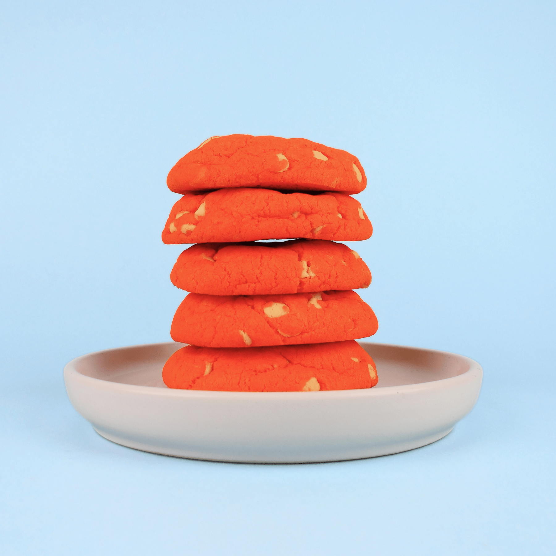 Stack of orange cookies on a beige plate with a blue background