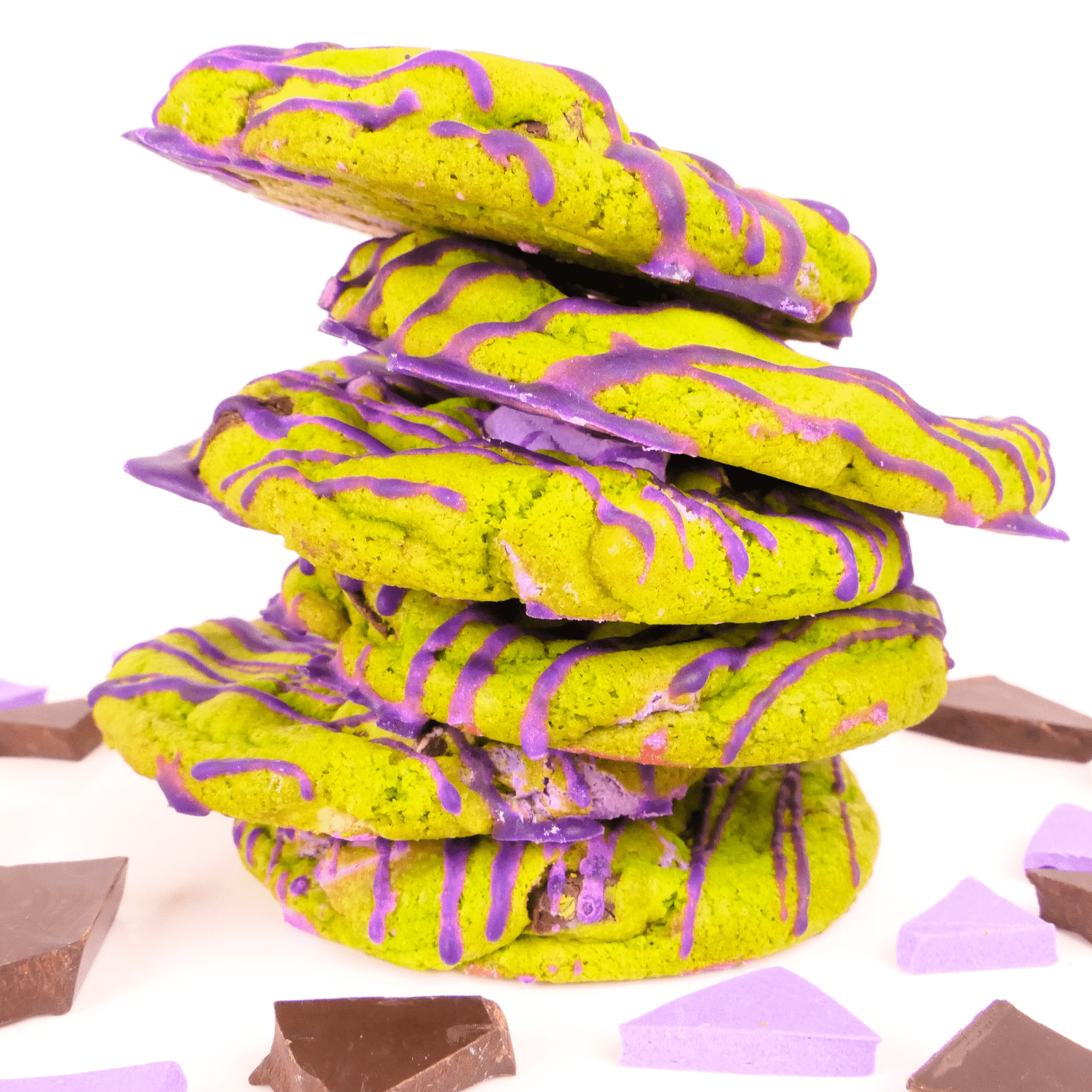 Green cookies with purple drizzle stacked on top of each other